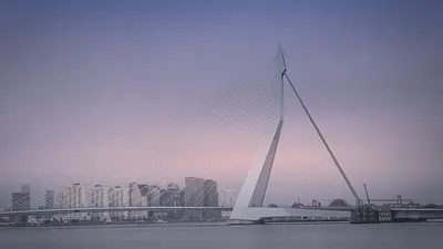 Langzeitbelichtung der Erasmusbrücke in Rotterdam bei Sonnenuntergang mit Graufilter-Effekt.